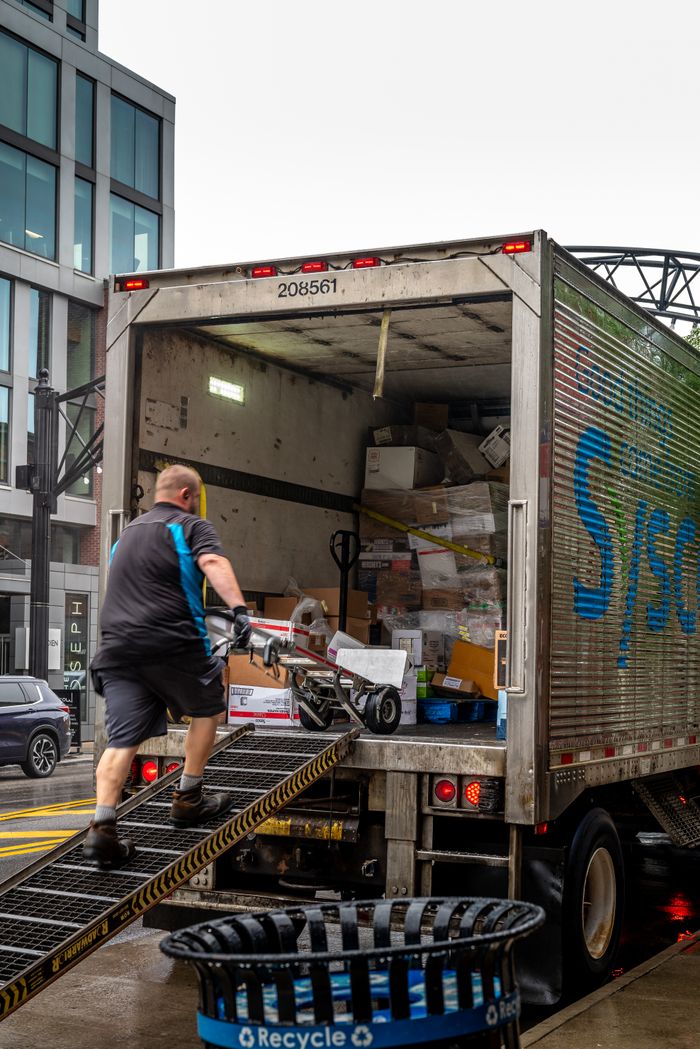 Crafting Captivating Headlines: Your awesome post title goes here A man loads packages into a delivery truck in a modern urban area.