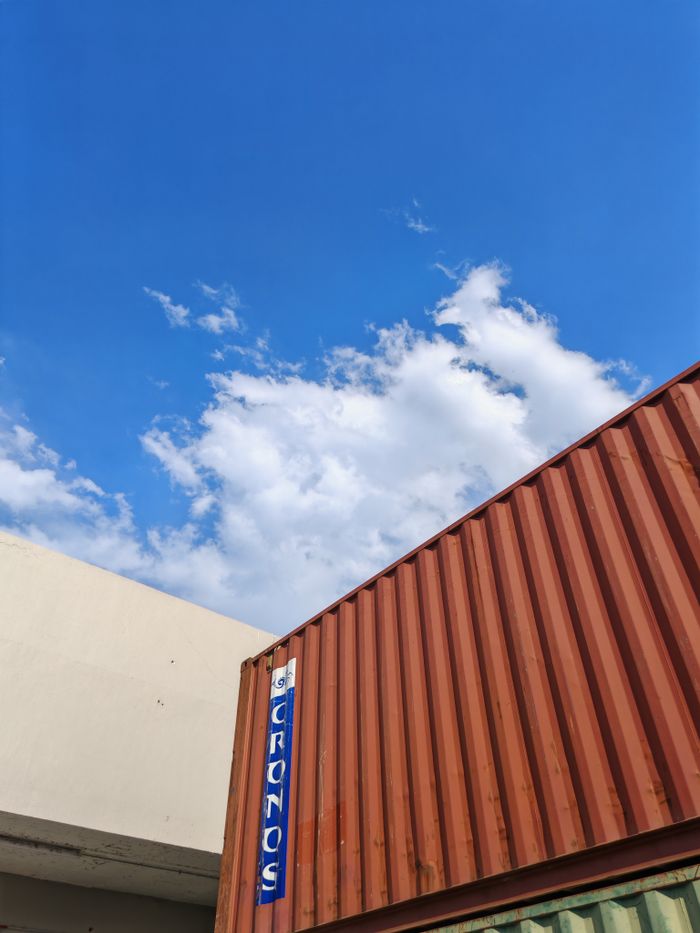 The Art of Drawing Readers In: Your attractive post title goes here Industrial shipping container under a bright blue sky with clouds.